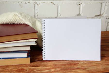Stack of books with woolen blanket on the wooden table with a copy space