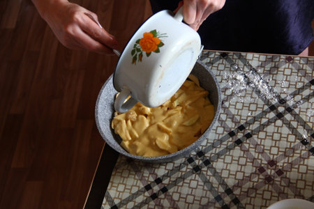 Young woman preparing pie with apples and pears on the kitchen table top viewの写真素材