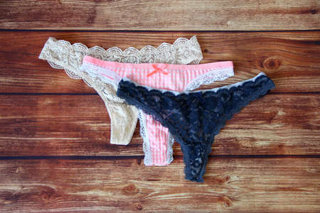Three lace sexy panties on the wooden background with a copyspace