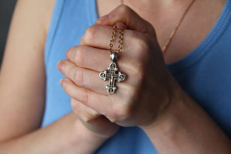 Golden Christian cross in the female hands, closeの写真素材