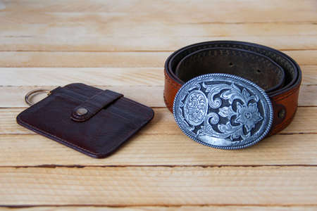 Leather cowboy belt and leather wallet on a wooden backgroundの写真素材