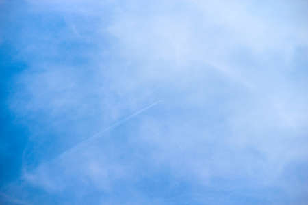 Plane flies high in the sky among the cloudsの写真素材