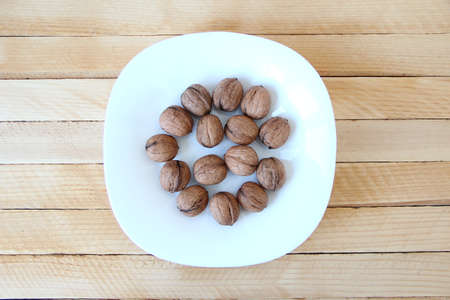 Walnuts in a plate on a wooden background