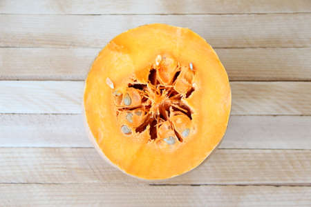 Cut pumpkin on wooden background, half pumpkin, top view