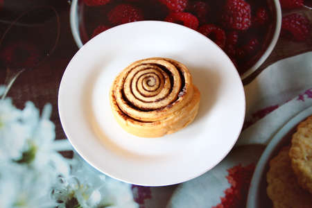 Appetizing cinnamon roll on the white plate