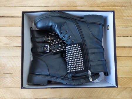 Black women's leather boots with rhinestonesin in the box on a wooden background