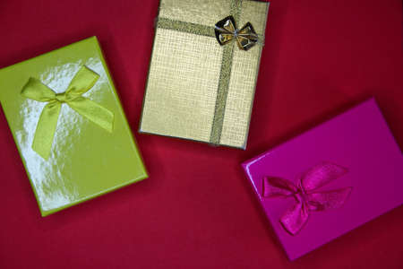 Three multicolored gift boxes on the red background