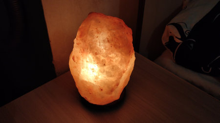 Salt lamp shines in the dark on a bedside tableの写真素材