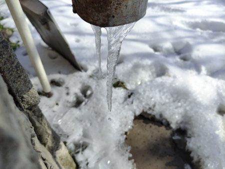 Icicle hangs under a drainpipe of a houseの写真素材