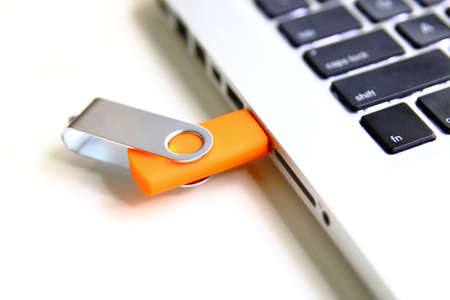 thumb drive into a laptop. isolated over whiteの写真素材