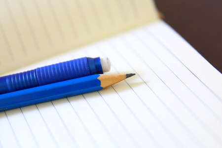 Drawing pencil and eraser over a white notebook, close-upの写真素材