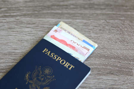 American passport with bank notes over a light grey wooden background