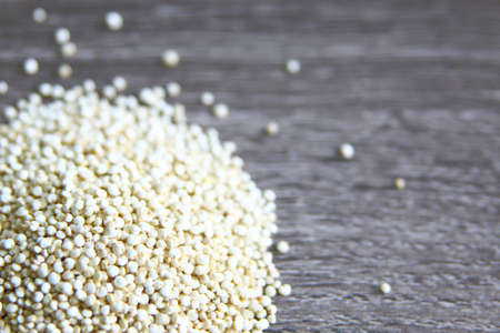 quinoa seeds over a light wood grey background