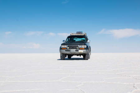 Car on the Uyuni Salar in Bolivia.  Blue Sky and white salt background. Uyuni, Bolivia