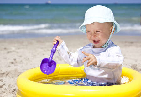 baby playing with toys in pool on a beachの写真素材