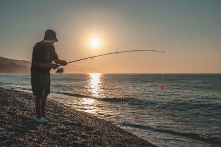 An old man fishing on the seashore at dawn in the Mediterranean Seaの写真素材