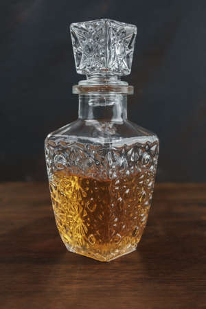 Bottle and glass with whiskey on aged wood and dark backgroundの写真素材