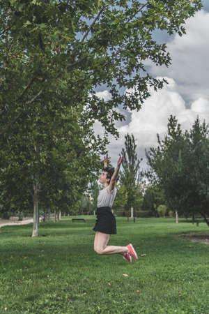 A woman jumps during a sunny day in the park