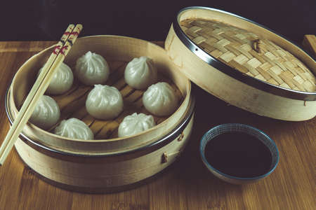 Traditional asian food. Steamed in a wooden steamer, on a dark background.の写真素材