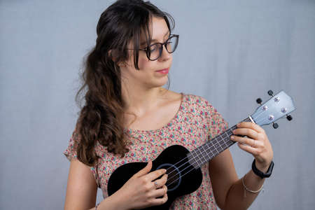 A girl with glasses playing the ukulele