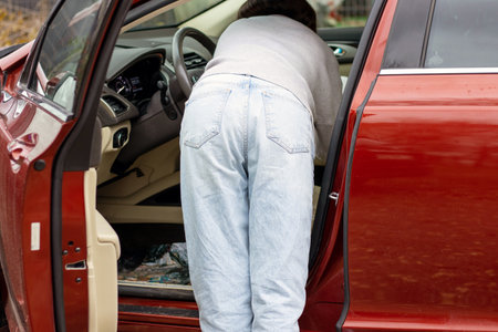 woman in front of lateral door red car in warm pullover blue jeansの写真素材