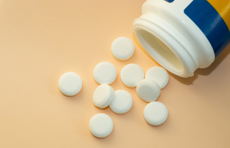 pills isolated medicine medical concept.white round red heart shaped pills chaotic or in row on green blue black orange paper from bottle disease treatment.arrow from tablets money coin plastic blisterの写真素材