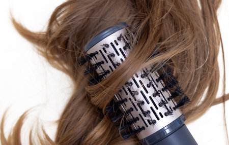 strand of woman blonde curly hair isolated and straightener,curling iron,dryer rotating brushの写真素材