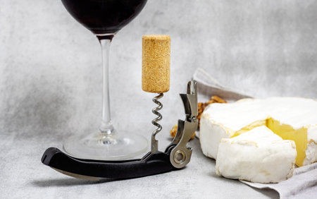 red wine in glass with brie cheese on edge,cork and crowscrewの写真素材