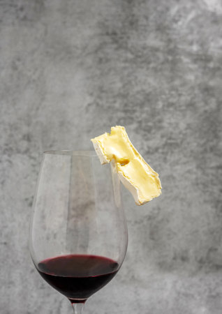 red wine in glass with brie cheese on edge,cork and crowscrew