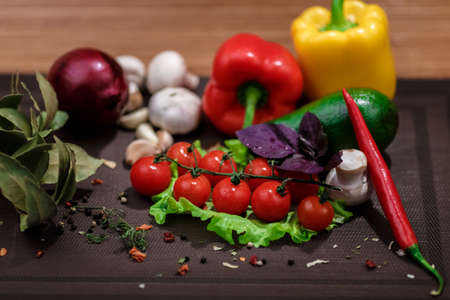 Fresh vegetables and spices: tomatoes, peppers, mushrooms, herbs, bread, avocado on wooden...