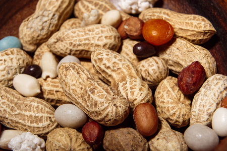 Peanuts with candies in wooden dish closeup macro