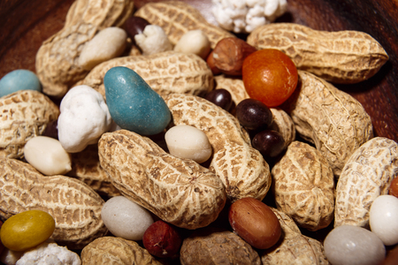 Peanuts with candies in wooden dish closeup macro