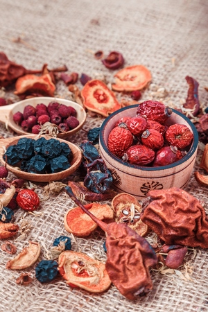 Dried fruit and berries in a wooden bowl on sacking background close-up macroの写真素材