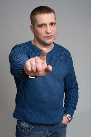 Closeup portrait open eyed young man, mad worker, pointing his finger against somebody at isolated grey background.の写真素材