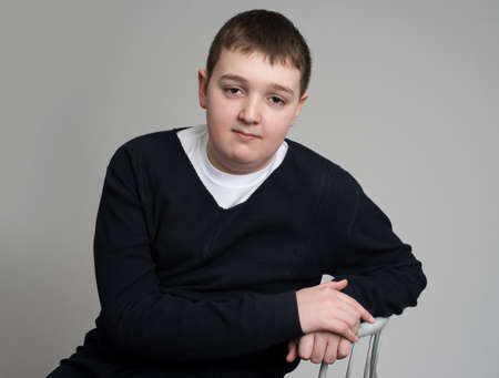 young caucasian old fashioned boy sitting on chair isolated over gray backgroundの写真素材