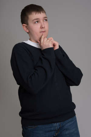 teenager boy brown hair European appearance and has difficulty thinking on a gray backgroundの写真素材
