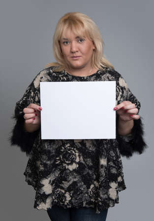 young woman holding empty white board, on a  grey backgroundの写真素材