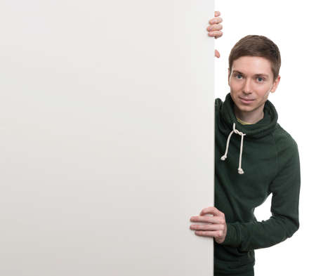 A smiling handsome male posing behind a white panel isolated on white backgroundの写真素材