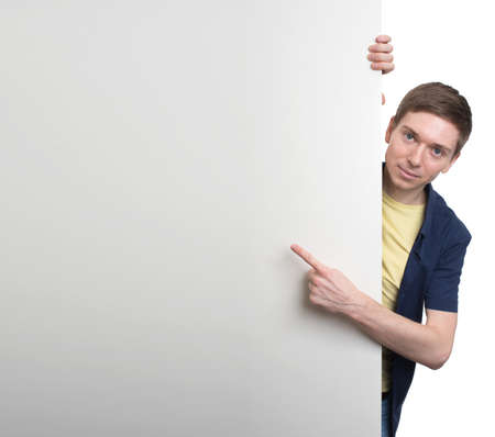 A smiling handsome male posing behind a white panel isolated on white backgroundの写真素材