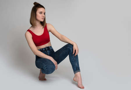 Portrait of a casual happy woman sitting on the floor on gray backgroundの写真素材
