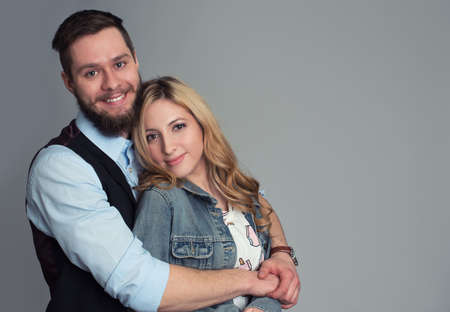 smiling young couple posing at the camera isolated on grayの写真素材