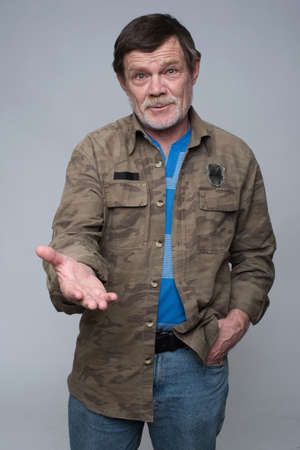 Handsome elderly man with gray beard shows on something isolated over white backgroundの写真素材