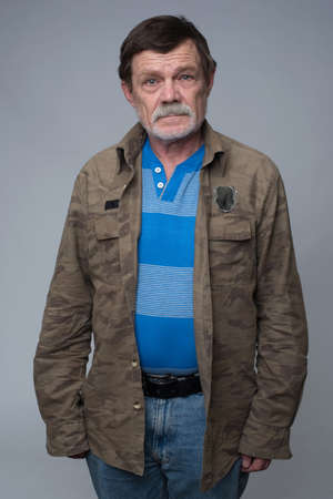 Older man standing with crossed arms and showing disapprovalの写真素材