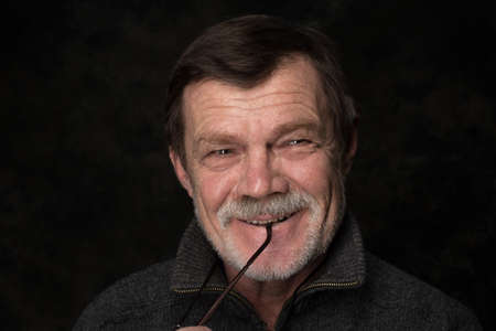 Closeup portrait of elderly man with beard on a black backgroundの写真素材