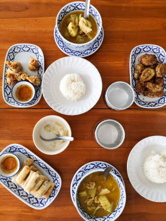 Thai dishes on a wooden table - Thai curry, rice, spring rolls, Thai golden bags. Thai food cooking class, Krabi, Thailandの写真素材