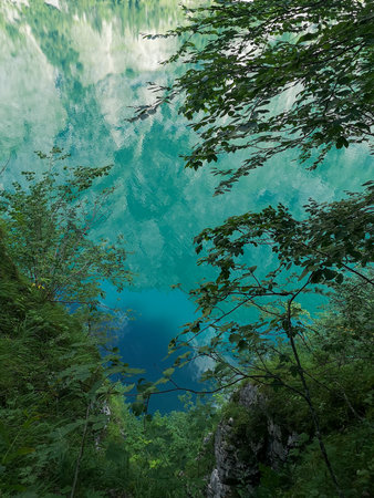 Reflection of the hills in the turquoise water of Obersee surrounded by treesの写真素材