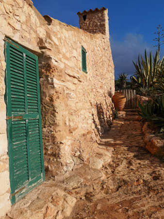 Mediterranean style of house made of stone with green doors lined by pathway with plants - Mallorcaの写真素材