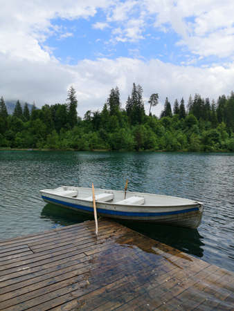Boat by a pier on Caumasee lake surrounded by trees - Flims, Switzerlandの写真素材