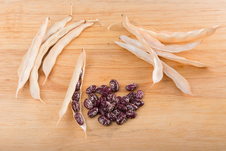 bunch of red beans and pods on a wooden cutting boardの写真素材