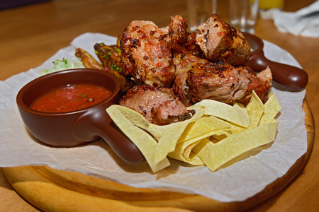 pieces of meat, garnish and sauce on a wooden standの写真素材